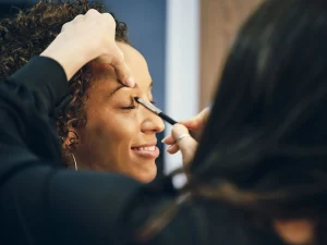 Jeune femme qui se fait maquiller par un maquilleur professionnel